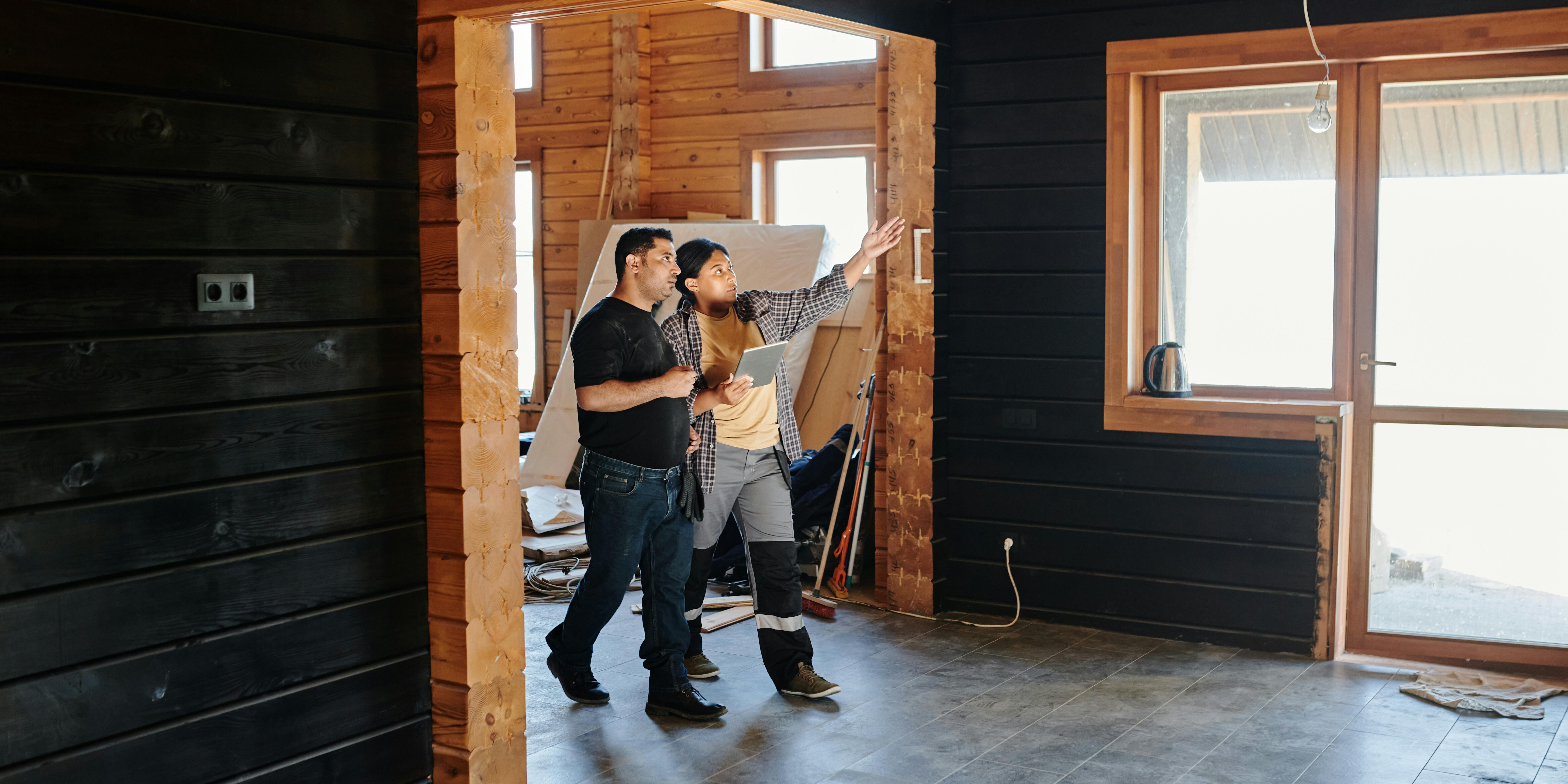 two people in a house under construction and with a paper in hand