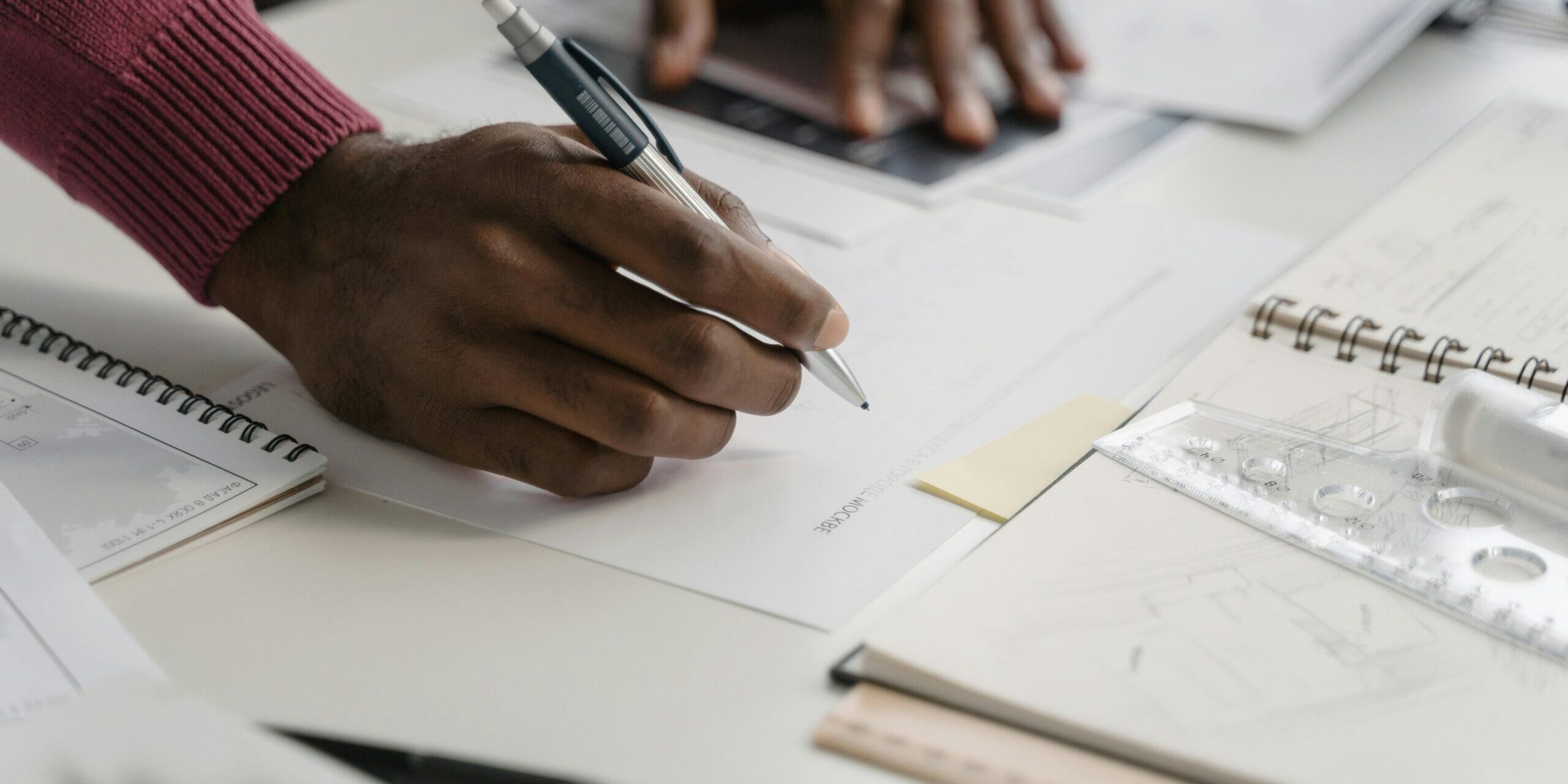 pexels-tima-miroshnichenko-6615294 Close of hands of a Black person working on plans.